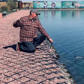 Рыболов с подсаком на облицованном берегу водоема